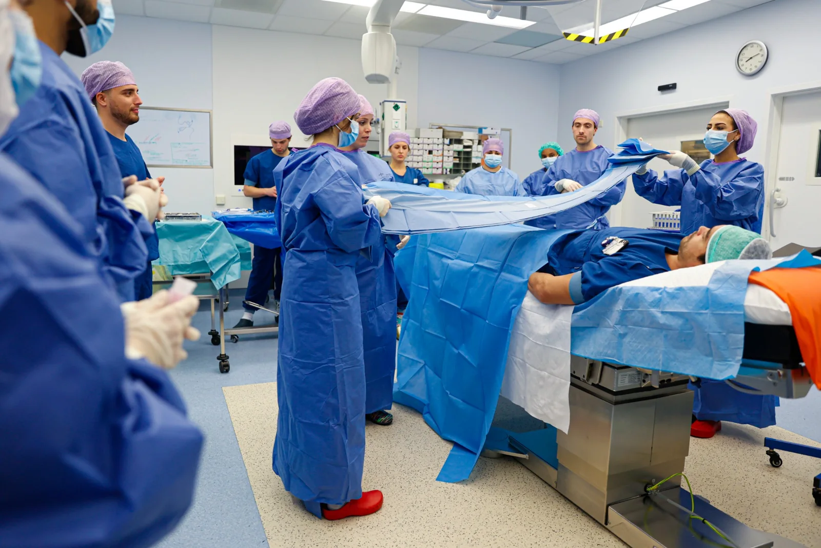 Studenten oefenen samen onder begeleiding met steriel afdekken.