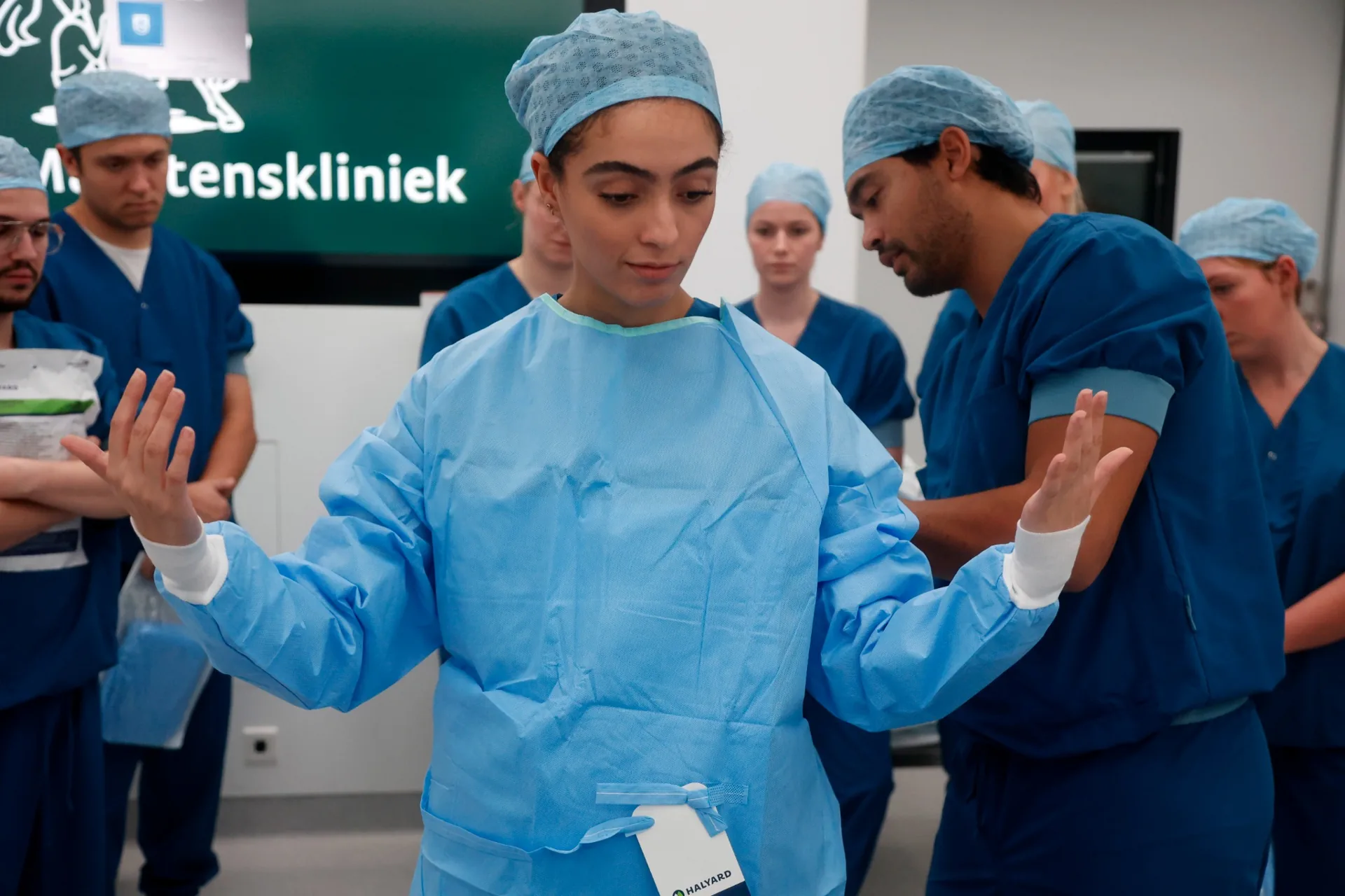 Een begeleider helpt een cursist bij het steriel aankleden.