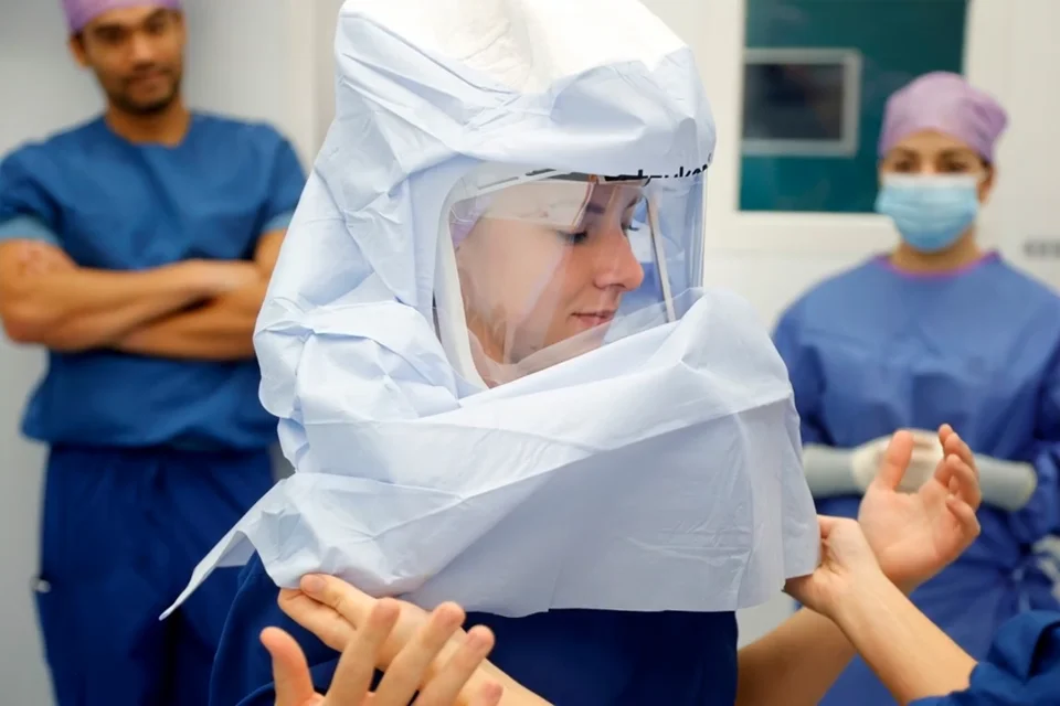 Een cursist trekt tijdens de cursus een steriele operatiejas aan.